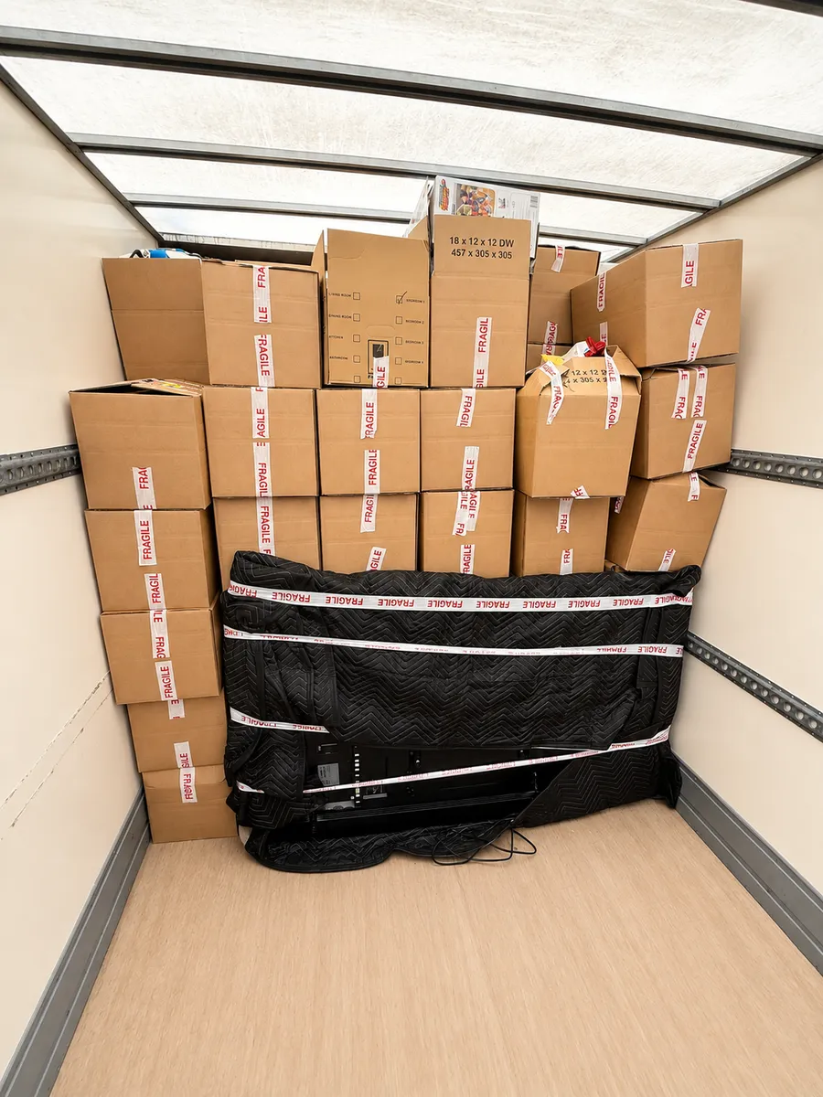 Boxes labelled fragile stacked neatly with a TV in a padded cover loaded in a Leaways Removals van