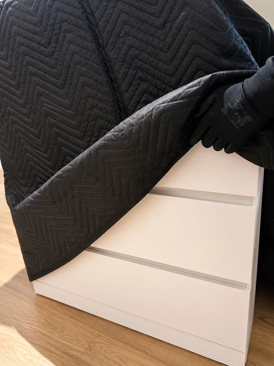 Leaways crew member protecting a chest of drawers with a quilted padded blanket