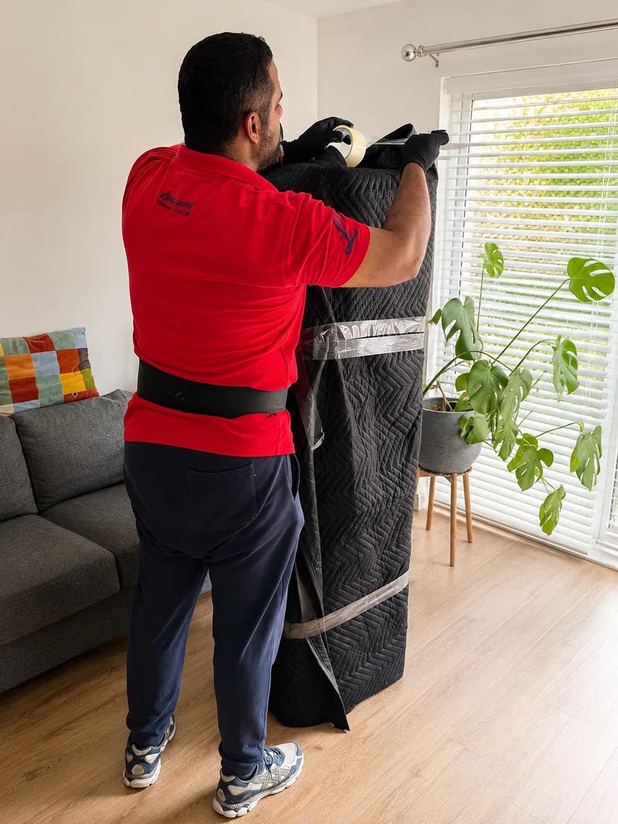 Leaways Removals crew wrapping a TV unit in protective material before loading