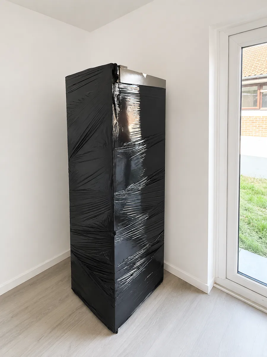 Tall fridge freezer wrapped in protective plastic film by Leaways Removals before moving