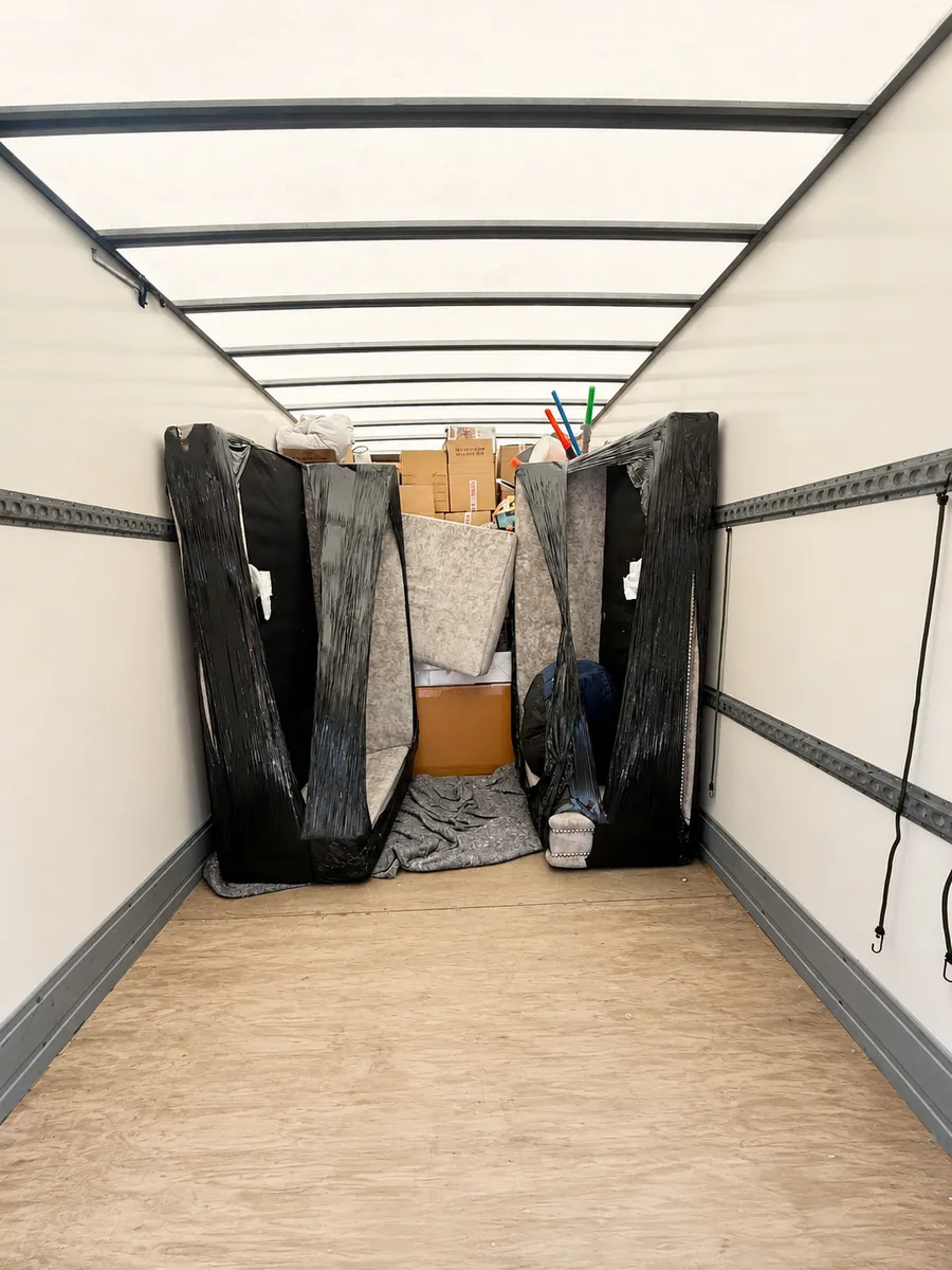 Sofas wrapped in protective film loaded and secured inside a Leaways Removals van