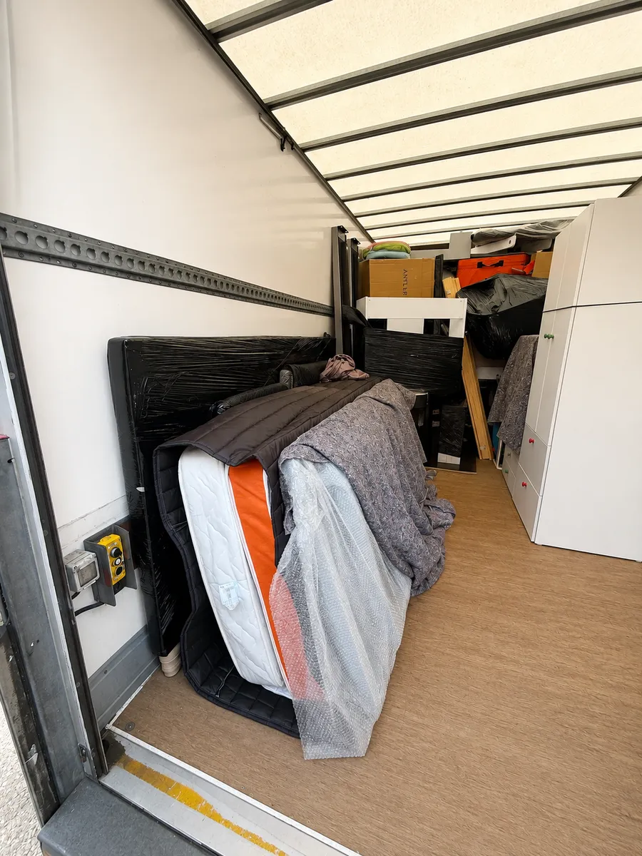 Mattress and bed frame wrapped and secured with padded covers in a Leaways Removals van