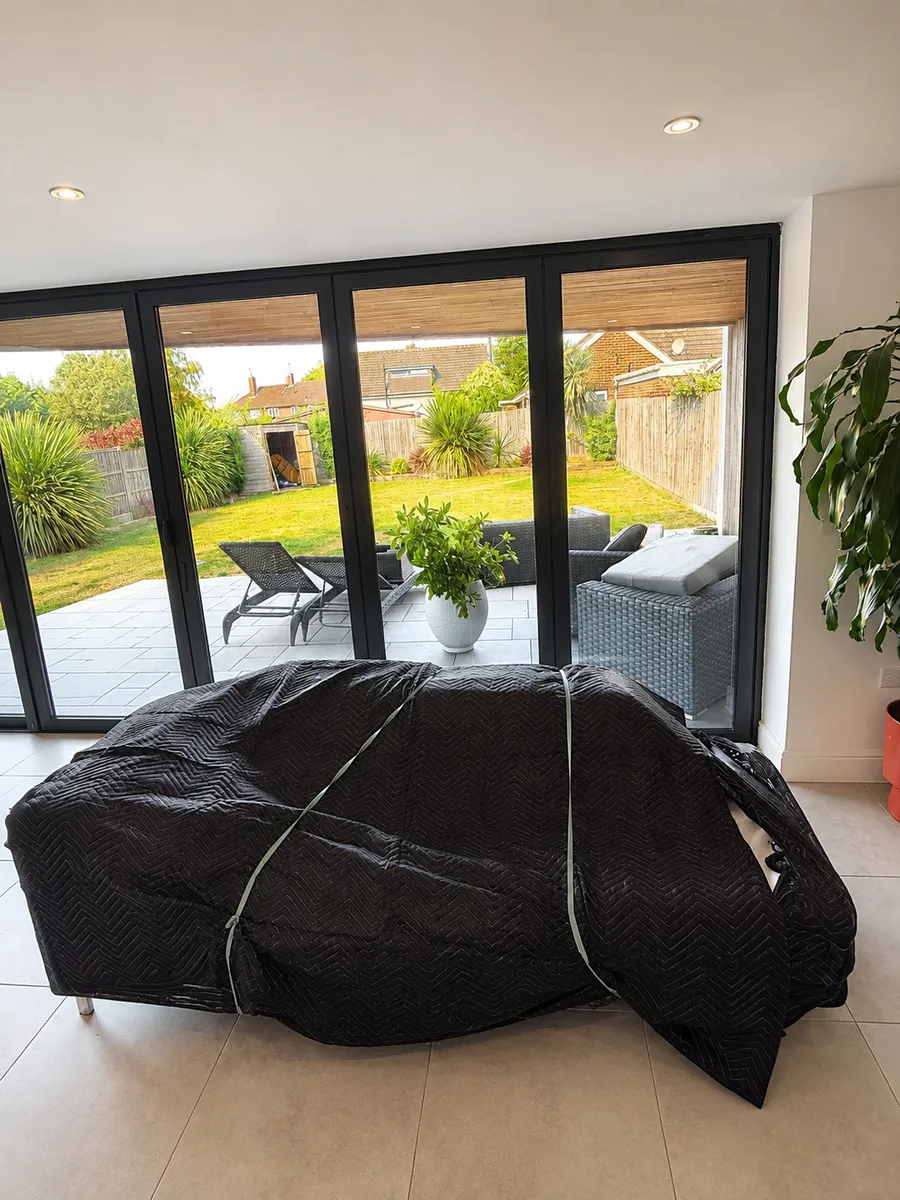 Large sofa wrapped securely in quilted moving blankets with bands by Leaways Removals